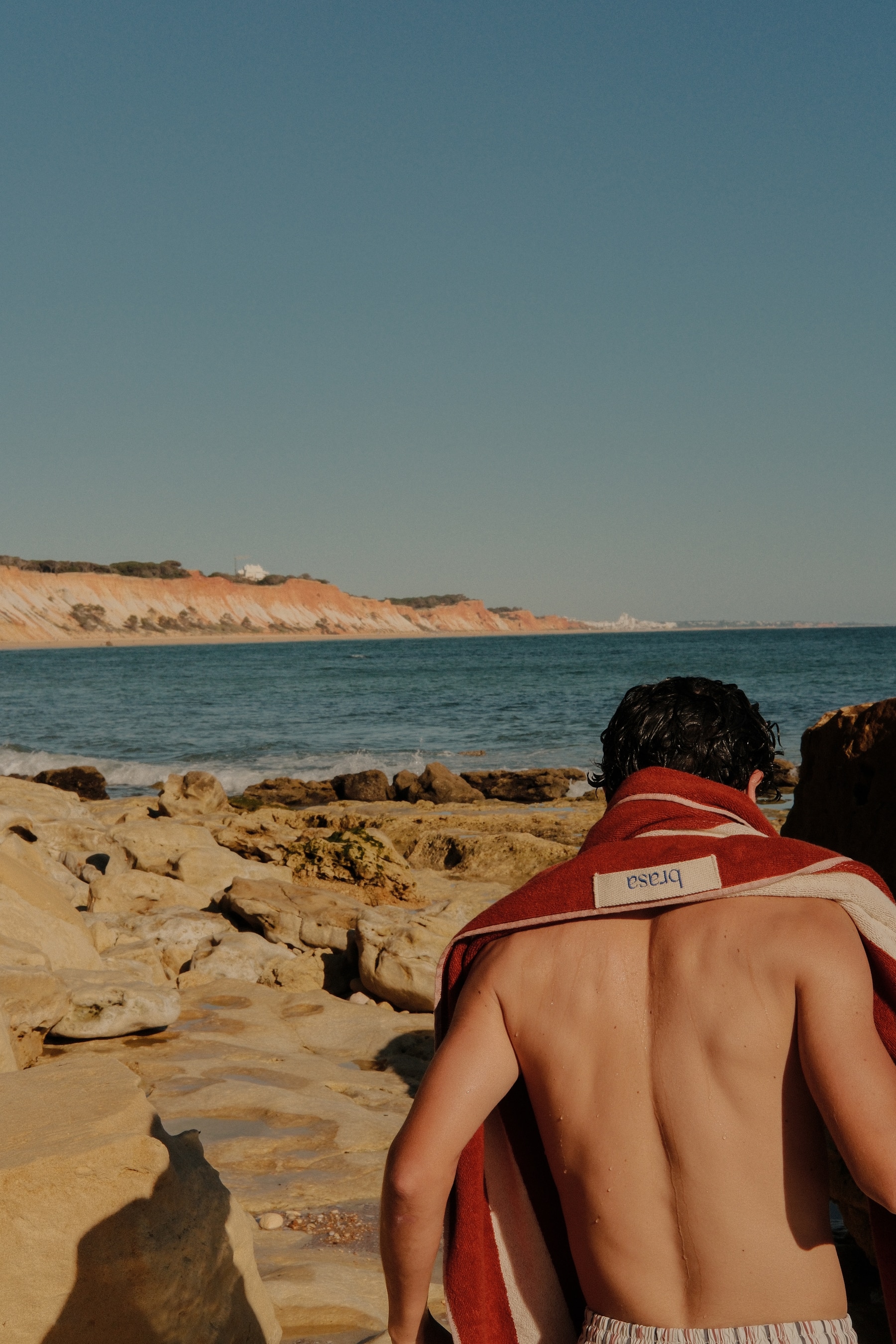 brasa Terracotta Towel over shoulders with Algarve cliffs behind